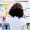 Woman looking at shelf of products at a drug store. 