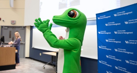 GEICO Gecko claps in front of lecture hall. 