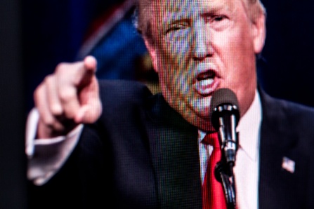 Photo of a TV screen with Donald Trump speaking while pointing. 